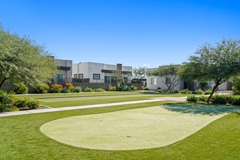 A yard with grass and trees and buildings in the background